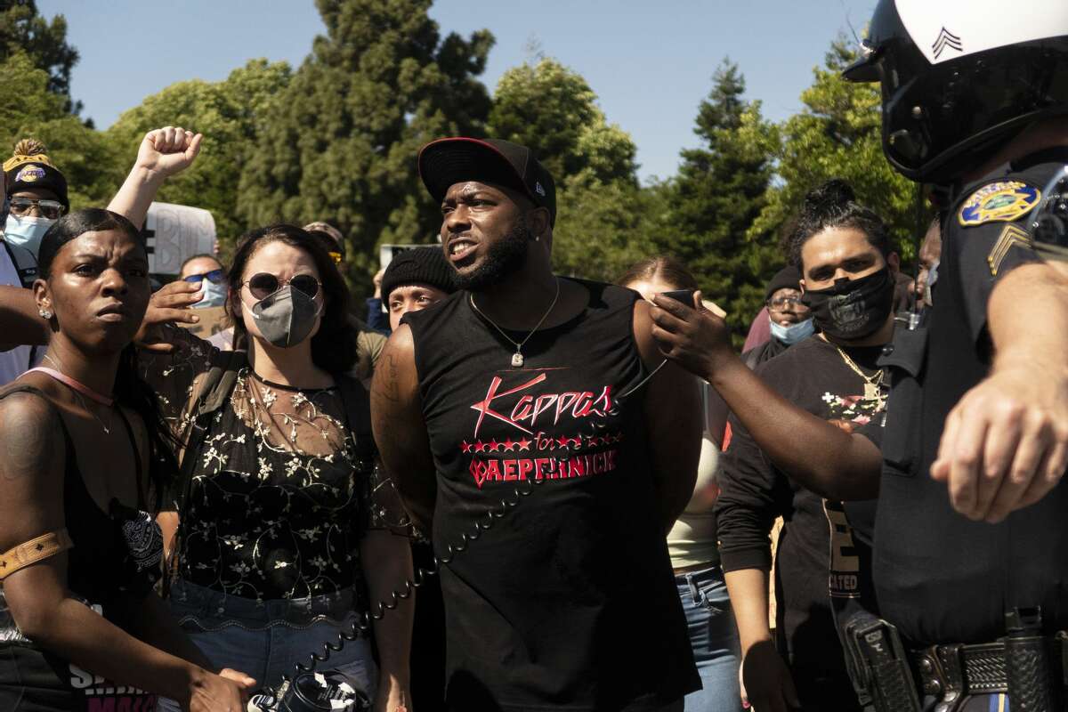 Brandon Coleman, center, talks to a crowd and Vallejo police officer Shane Bowers during a demonstration in Vallejo.