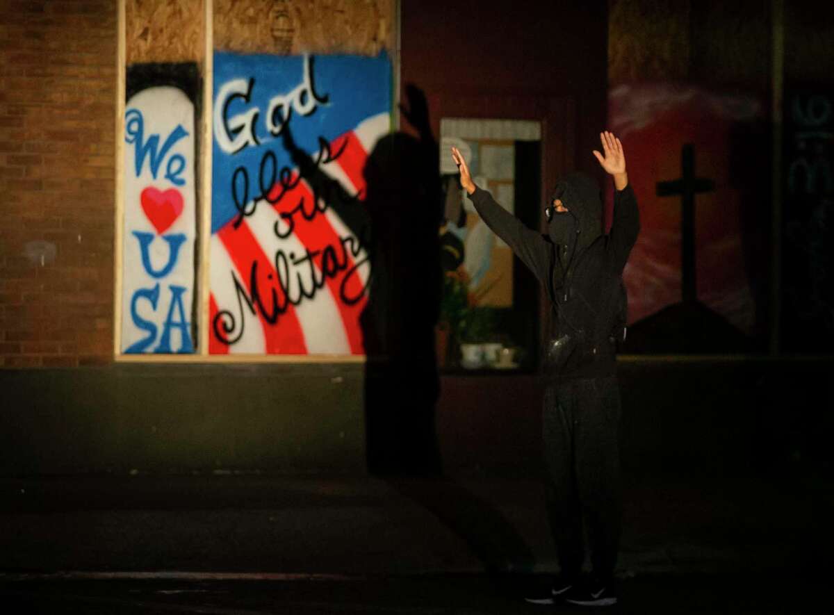 A person holds up his hands in front of law enforcement after an eruption of chaos when San Antonio Police fired rubber and wooden bullets and smoke and tear gas at demonstrators in downtown San Antonio, Texas, on June 2, 2020. Local activist groups planned another protest of the death of George Floyd, a Minneapolis man who died in the custody of a Minneapolis police officer May 25.