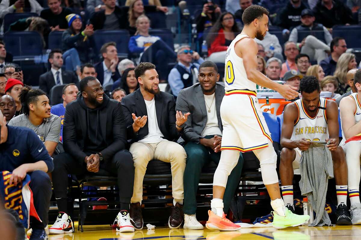 Golden State Warriors' Draymond Green, Klay Thompson and Kevon Looney react to Stephen Curry in 2nd quarter against Toronto Raptors during NBA game at Chase Center in San Francisco, Calif., on Thursday, March 5, 2020.