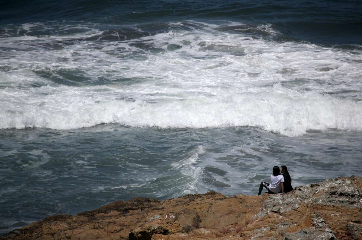 SAN FRANCISCO, CALIFORNIA - MAY 26: A couple sits on a rock overlooking Ocean Beach on May 26, 2020 in San Francisco, California.
