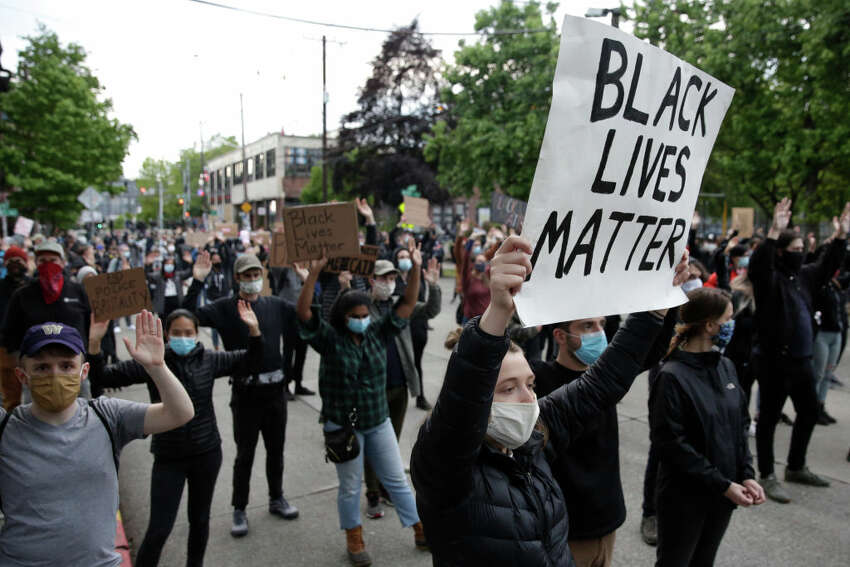 People hold up placards to protest over the death of George Floyd, an unarmed African-American man who died in police custody in Minneapolis on May 25, outside the Seattle Police Department's East Precinct in Seattle, Washington on June 2, 2020. - Protesters defied curfews across the United States on June 2 as leaders scrambled to stem anger over police racism while President Donald Trump rejected criticism over his use of force to break up a peaceful rally. (Photo by Jason Redmond / AFP) (Photo by JASON REDMOND/AFP via Getty Images)