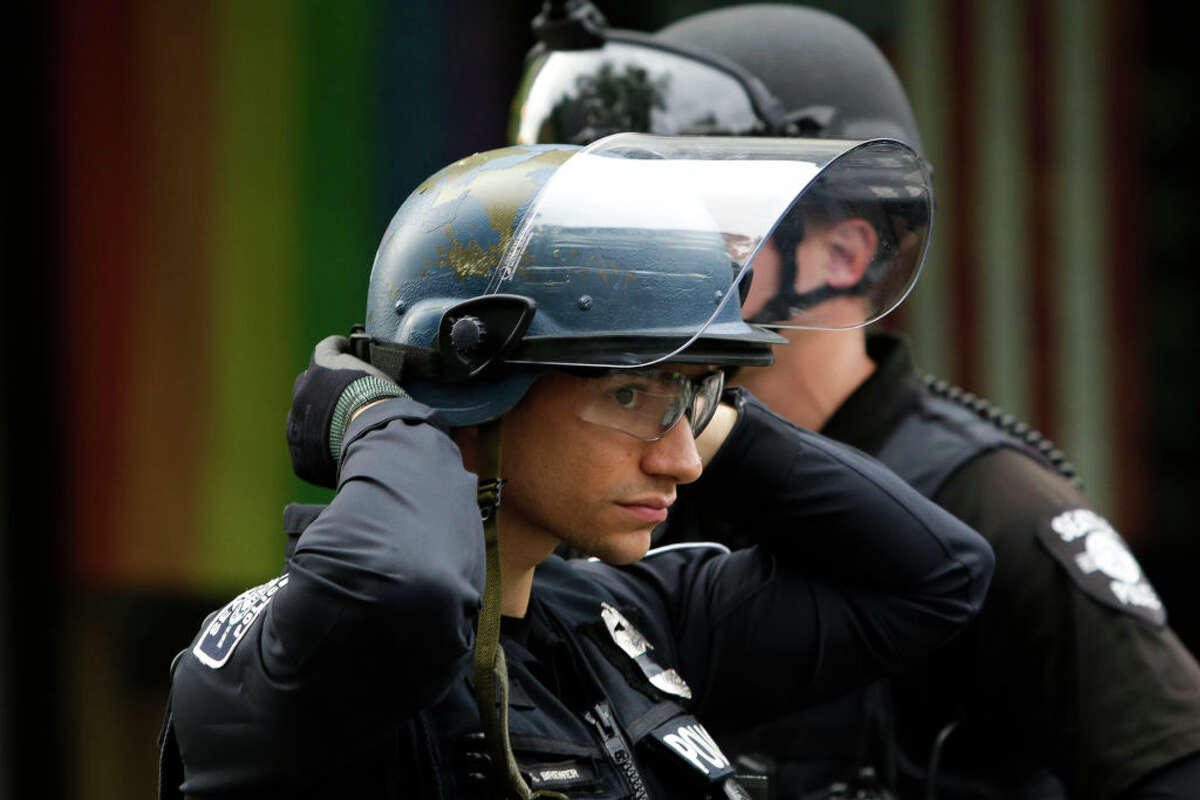 A police officer adjusts his helmet at a barricade as people protest nearby over the death of George Floyd, an unarmed African-American man who died in police custody in Minneapolis on May 25, outside the Seattle Police Department's East Precinct in Seattle, Washington on June 2, 2020. - Protesters defied curfews across the United States on June 2 as leaders scrambled to stem anger over police racism while President Donald Trump rejected criticism over his use of force to break up a peaceful rally. (Photo by Jason Redmond / AFP) (Photo by JASON REDMOND/AFP via Getty Images)