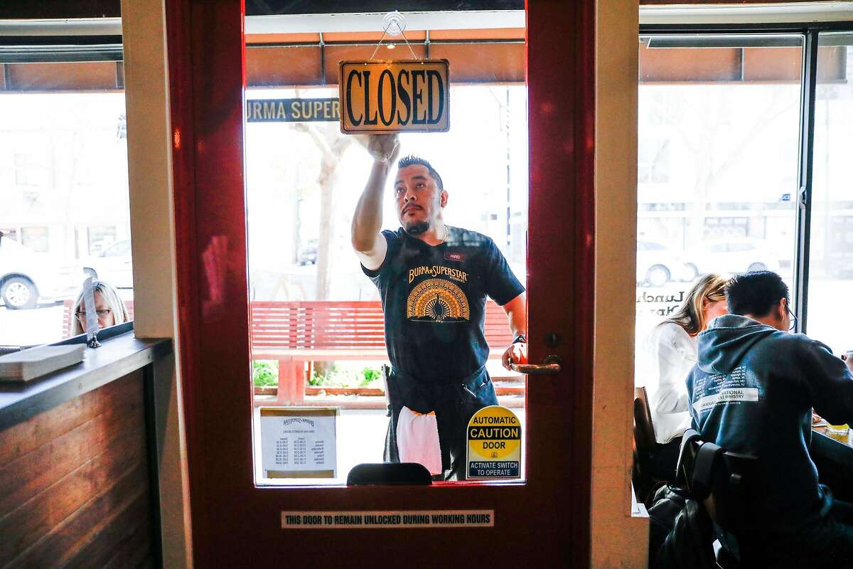 An employee named Farid cleans the windows as Burma Superstar as it opens for service Oakland, California, on Thursday, Feb. 20, 2020.