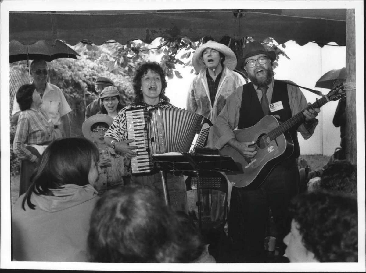 Old Songs Festival. Lou and Peter Berryman of Madison, Wisconsin, singing their own composition, "Why am I painting the living room" during song fest at Altamont Fairgrounds in New York Saturday afternoon. Behind them wearing the noreaster cap is folksinger Michael Cooney of Rockport, Maine, who joined in on the chorus. June 23, 1990 (John Carl D'Annibale/Times Union Archive)