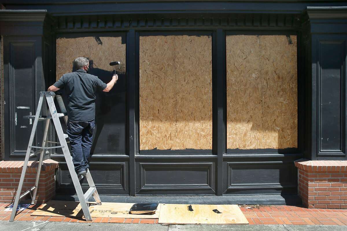 Mike Butler paints plywood boards covering the windows of an historic building on Georgia Street in Vallejo, Calif. on Wednesday, June 3, 2020. National Guard troops were deployed in Vallejo Tuesday night as the police station became overwhelmed by crowds massing in the streets.