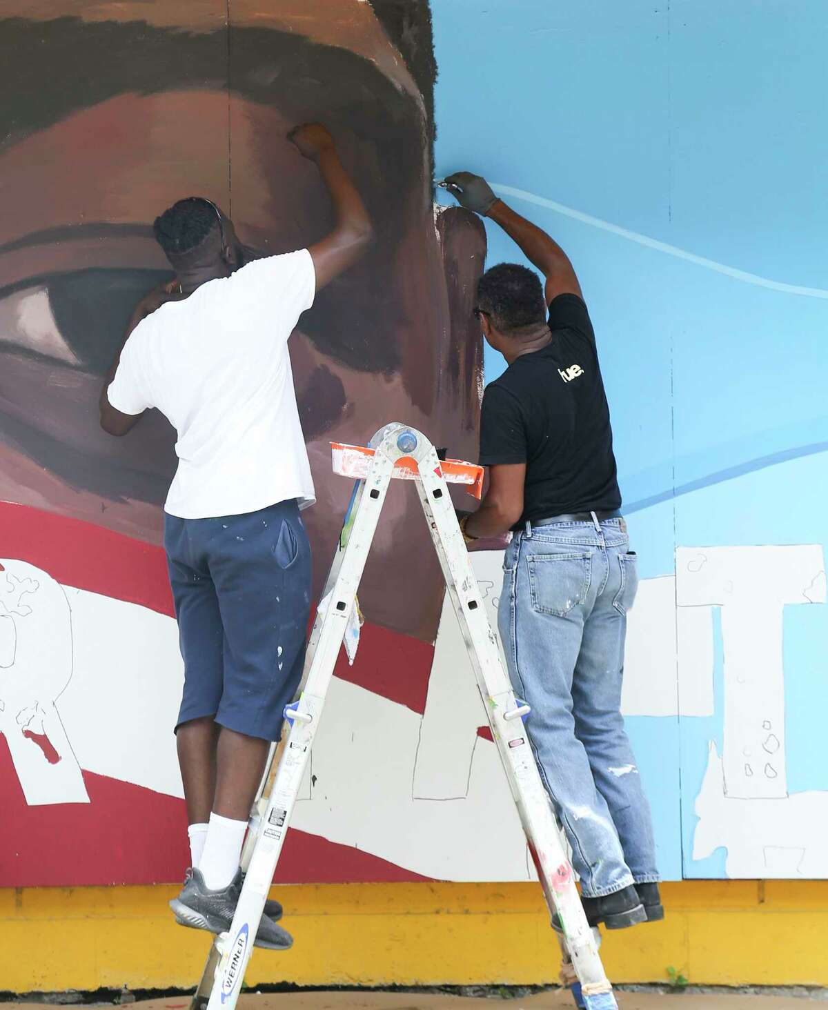 Artists Matthew Jeanbaptiste, left, and Reginald C. Adams, work on a mural inspired by George Floyed, on the side of the Breakfast Klub in Midtown on Tuesday, June 2, 2020.