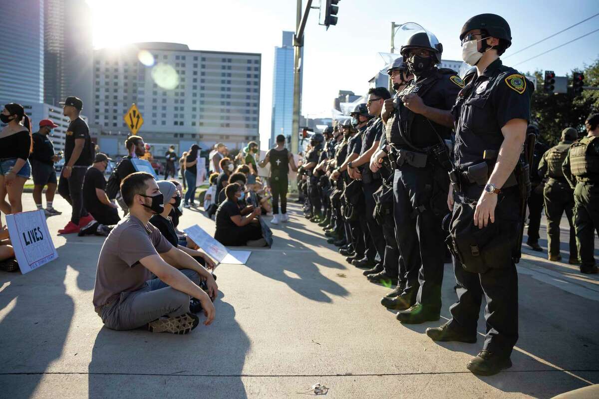 Demonstrators sit in front of Houston Police Department officers in downtown Houston, Tuesday, June 3, 2020. An estimated 60,000 people attended the rally in support of George Floyd and police reform.