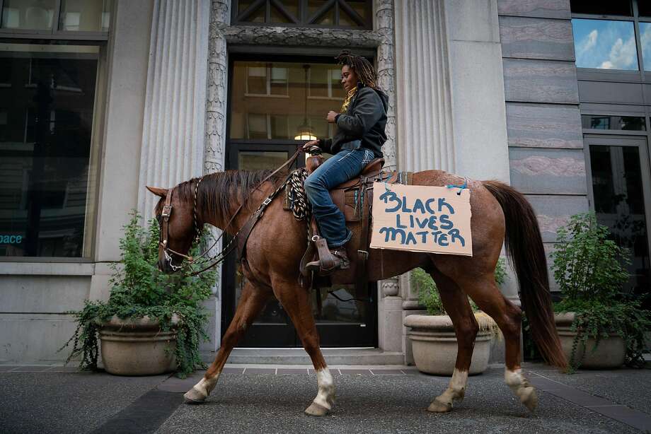 Brianna Noble, 25, rides her horse named Dapper Dan, through the streets of downtown Oakland at the start of a protest honoring George Floyd on Friday, May 29, 2020 in Oakland. "There is no image bigger than a black woman on a large horse," said Noble. "This is the image we would like to see portrayed in our community." Photo: Sarahbeth Maney / Special To The Chronicle