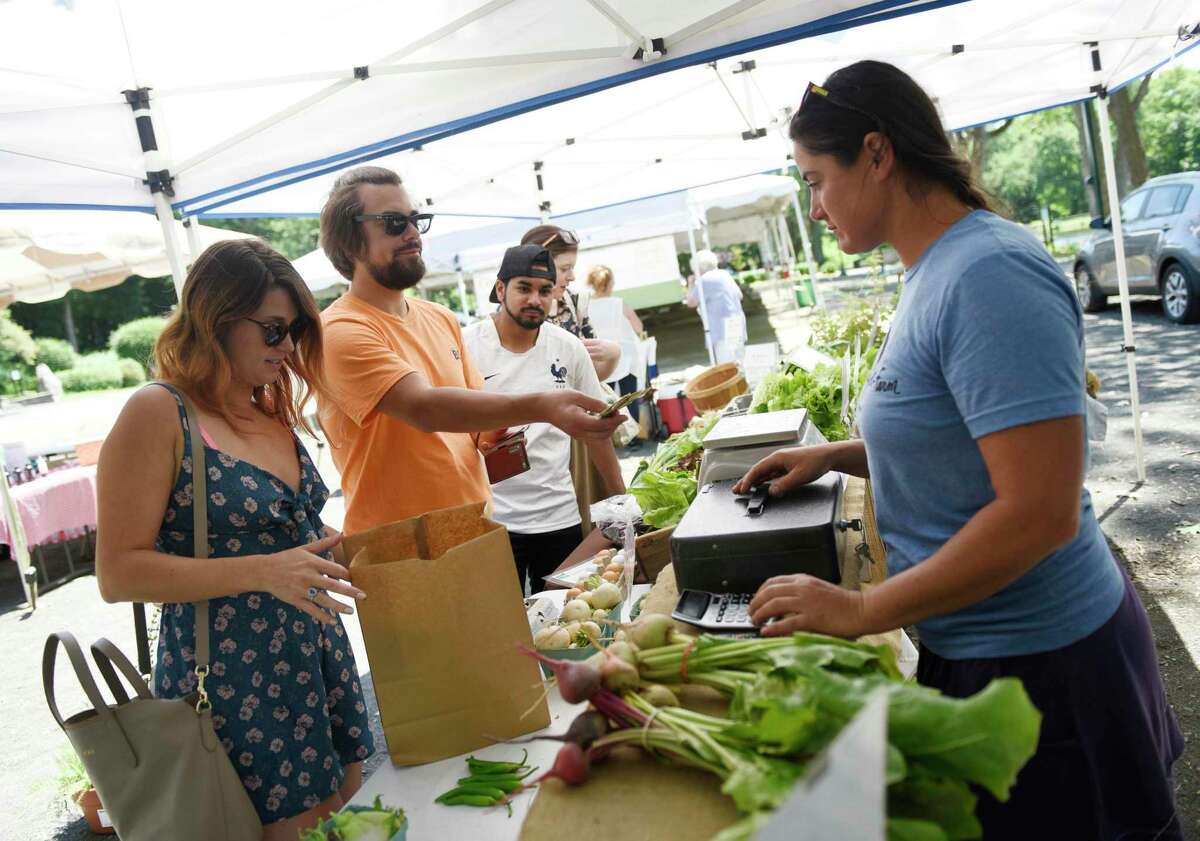 Customers browse the selection of the Muddy Roots Farm stand at the Stamford Museum & Nature Center Sunday Farm Market in Stamford, Conn. Sunday, June 30, 2019.