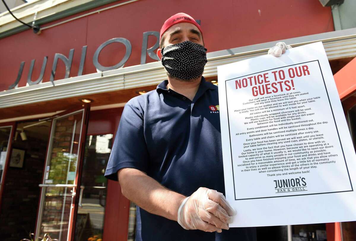 Brian Viglucci, co-owner of Juniors, holds a set of rules for the restaurant and customers as he cleans and sets up for outdoor dining which reopens today on Thursday, June 4, 2020 in Albany, N.Y. (Lori Van Buren/Times Union)