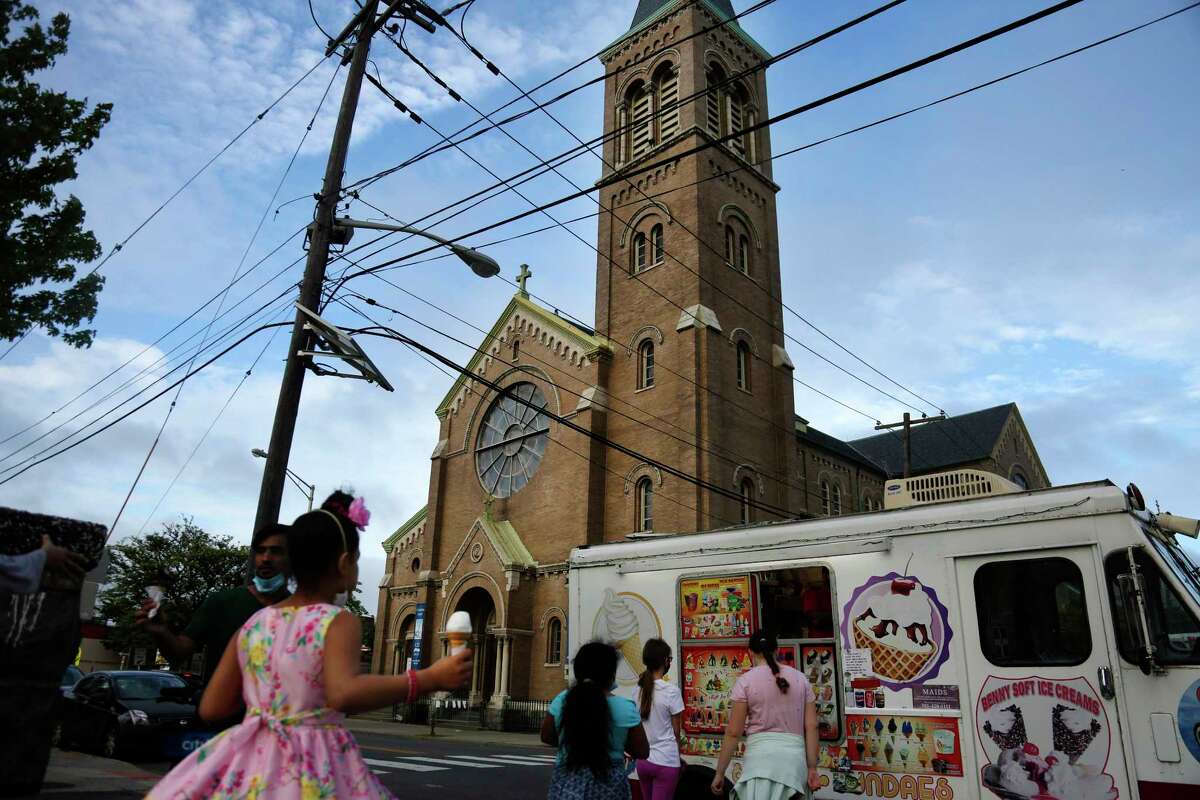 In this May 28, 2020, photo, people buy ice cream across the street from St. Nicholas Church in Jersey City, N.J. Mitchell Garabedian, an attorney for two alleged victims of RomanA Catholic Bishop Nicholas DiMarzio, told the Associated Press that Samier Tadros, 46, stepped forward after hearing that another man, 57-year-old Mark Matzek, had accused DiMarzio of sexually abusing him in the mid-1970s, when he was assigned to St. Nicholas Church. Joseph Hayden, DiMarzioas attorney, said he has evidence showing the accusations made by both men are false. (AP Photo/Jessie Wardarski)