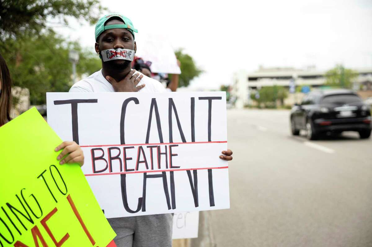 A demonstrator holds a sign against oncoming traffic at the intersection of 105 and Frazier in Conroe, Sunday, May 31, 2020. A rally was held in response to George Floyd's death which has sparked numerous protests throughout the country.
