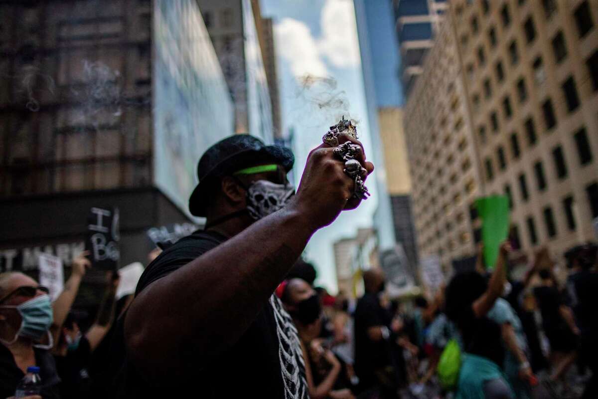 A man burns sage as he joins George Floyd's family in a march Tuesday from Discovery Green to City Hall in downtown Houston.