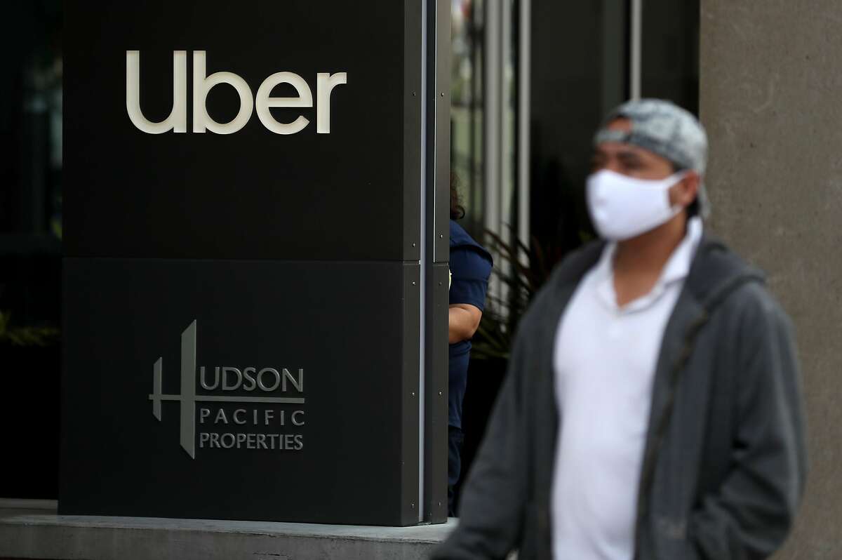 SAN FRANCISCO, CALIFORNIA - MAY 18: A pedestrian walks by a sign in front of the Uber headquarters on May 18, 2020 in San Francisco, California. Uber announced plans to cut 3,000 jobs and shutter or consolidate 40 offices around the world due to severely declining business as the coronavirus (COVID-19) pandemic continues. The cuts come two weeks after Uber cut 3,700 employees. (Photo by Justin Sullivan/Getty Images)