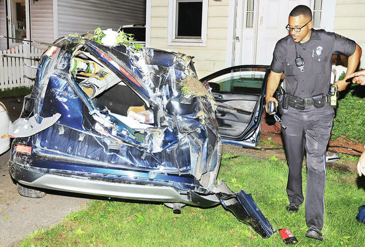 An Alton Police officer checks out the Honda SUV, model unidentifiable, that stuck the guardrail on the curve from Milton Road to westbound Brown Street about 10:15 Friday night. The vehicle flipped multiple times, struck a parked car in a driveway and stopped just short of hitting a house, seriously injuring the driver and lone occupant in the vehicle.