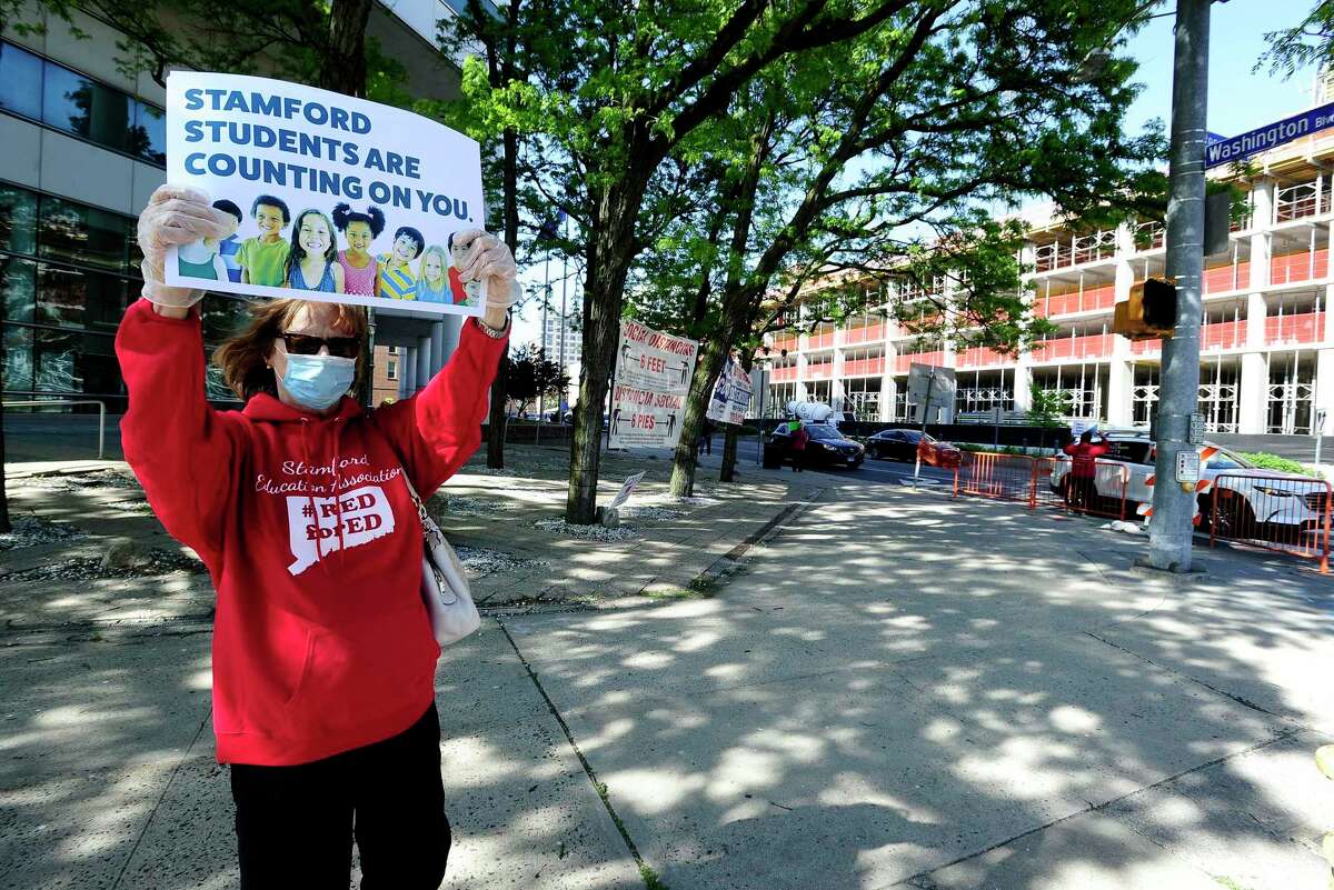 Diane Phanos, president of Stamford teachers union, holds a sign during a rally at the Stamford Government Center on May 21, 2020.