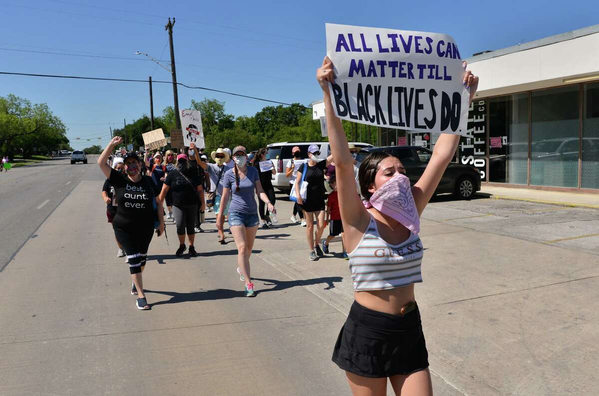 Protesters carry signs during a Black Lives Matters march along Broadway St. through Alamo Heights Saturday morning.