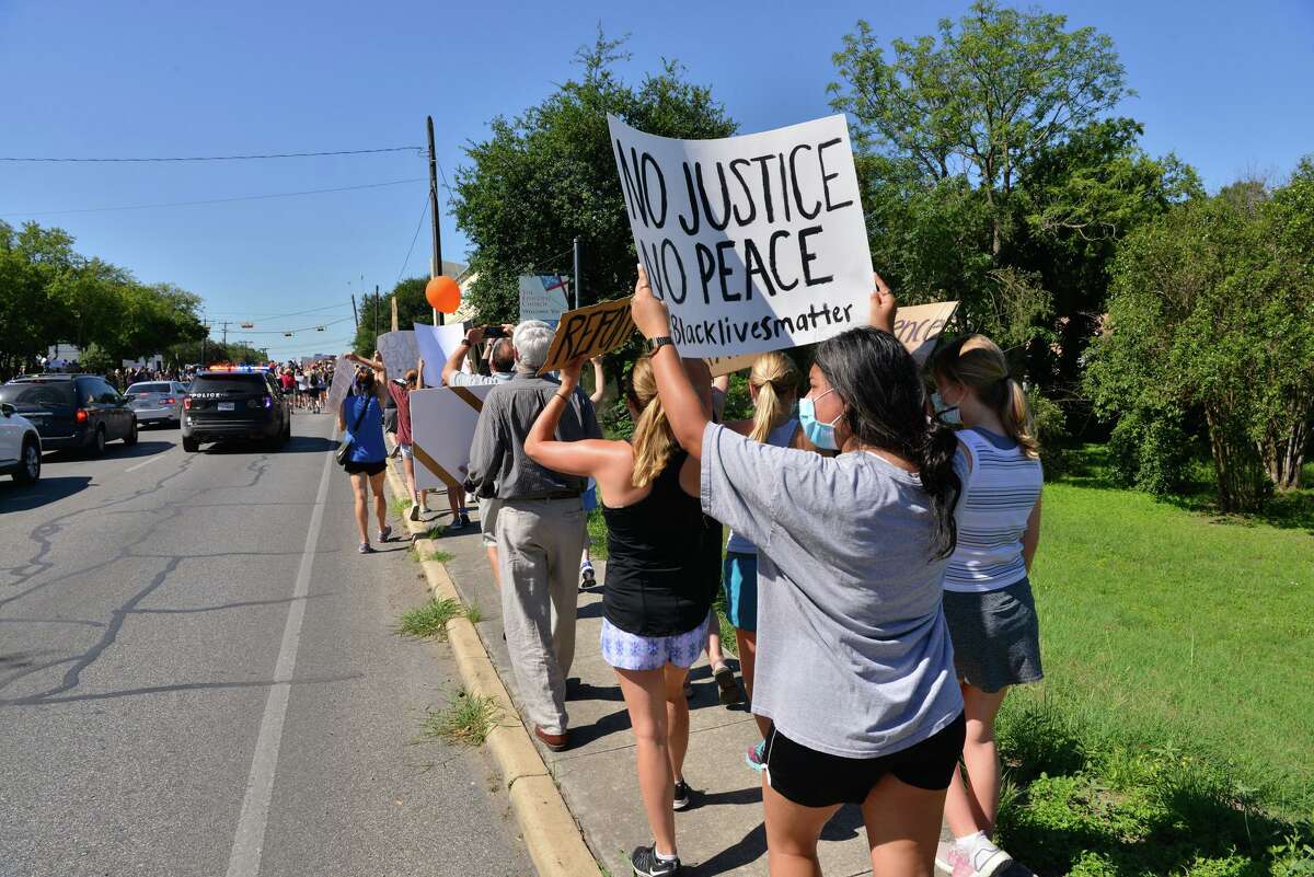 Protesters carry signs during a Black Lives Matters march along Broadway St. through Alamo Heights Saturday morning.