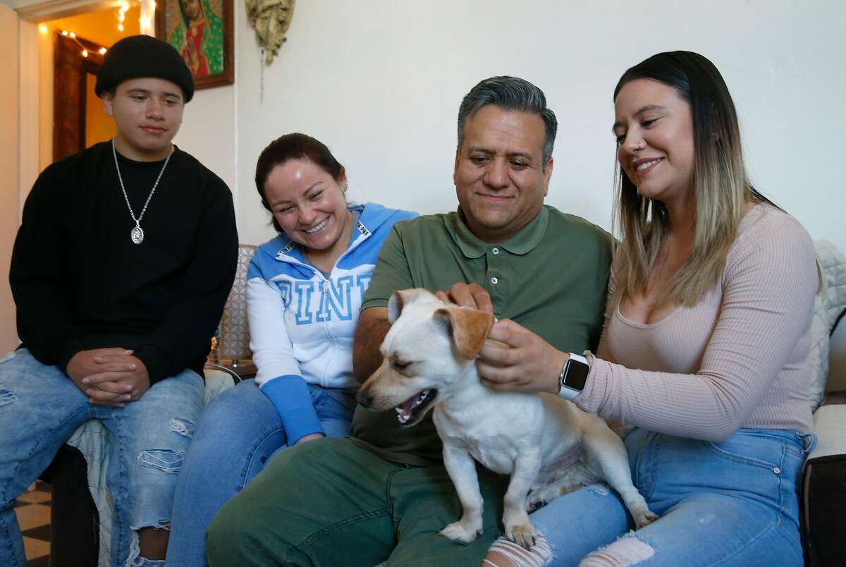 Samuel Ramirez and daughter Jenny pet Snoopy as son Fabian and wife Maria watch in San Francisco, Calif. on Saturday, June 6, 2020. The Ramirez family is concerned with being evicted from their Mission District apartment as Samuel struggles to find work as a cook during the coronavirus pandemic.