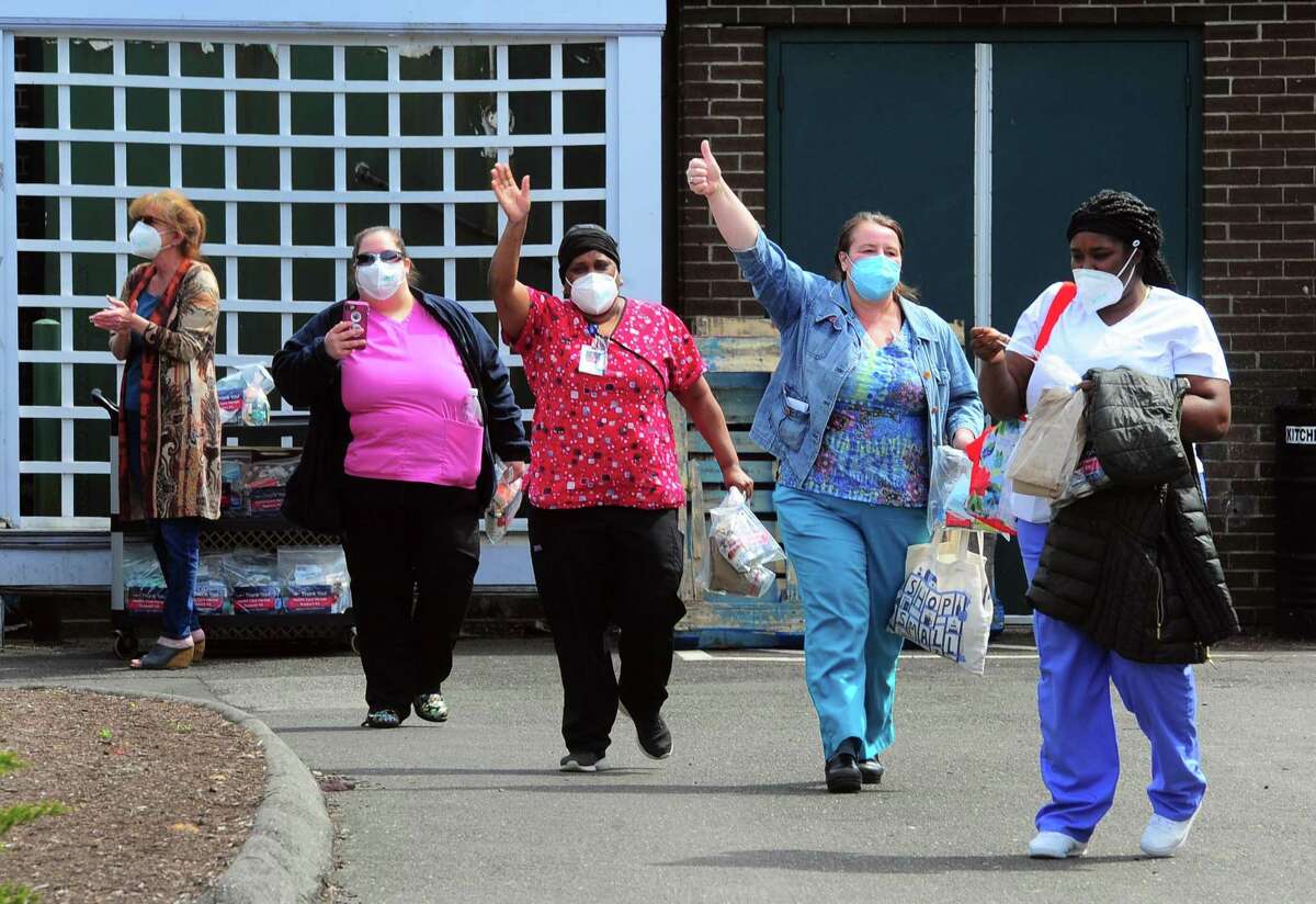 Health care workers wave during a cheer line set up to honor employees at Bishop Wicke nursing home on Long Hill Ave in Shelton, Conn., on Thursday May 14, 2020.