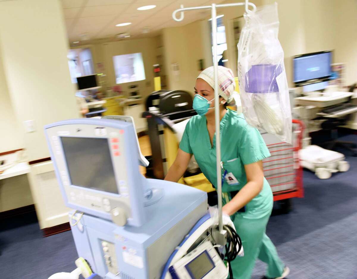 Respiratory therapist Jennyfer Ramirez wheels a ventilator through the intensive care unit where coronavirus patients are being treated at Greenwich Hospital.