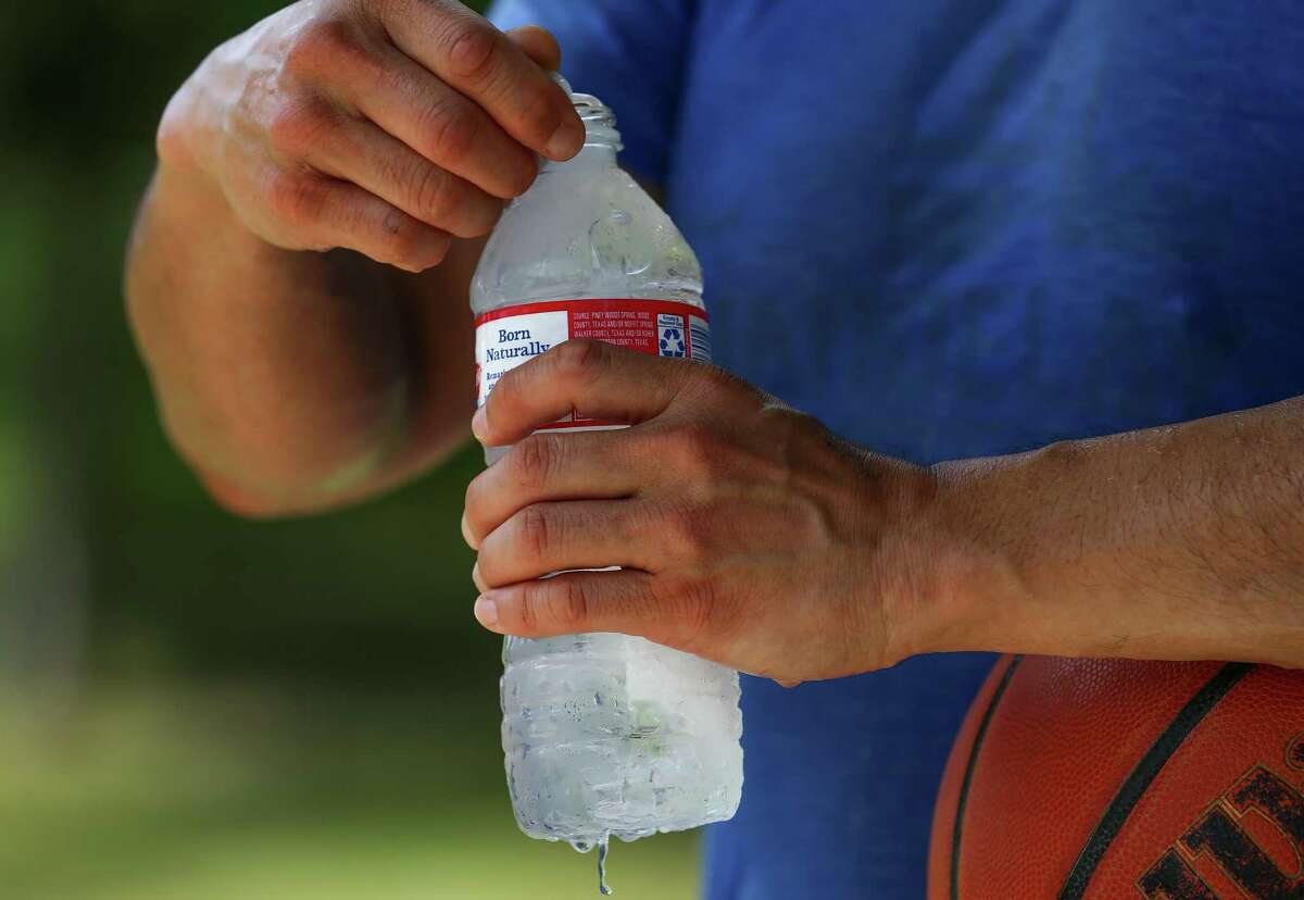 Kwang K. opens a bottle of iced cold water while taking a break from playing basketball at Spotts Park Wednesday, Aug. 7, 2019, Houston. A heat advisory was placed in the area with the heat index expected to be between 105 and 110 degrees.