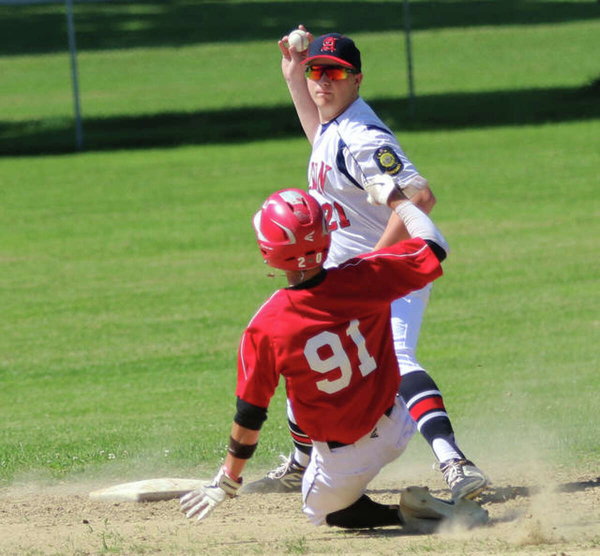 Alton second baseman Gage Booten throws to first base, but cannot complete a double play after getting the force on Highland’s Landyn Oestringer (91) at second on Sunday at P.I.C. Park in Pierron.