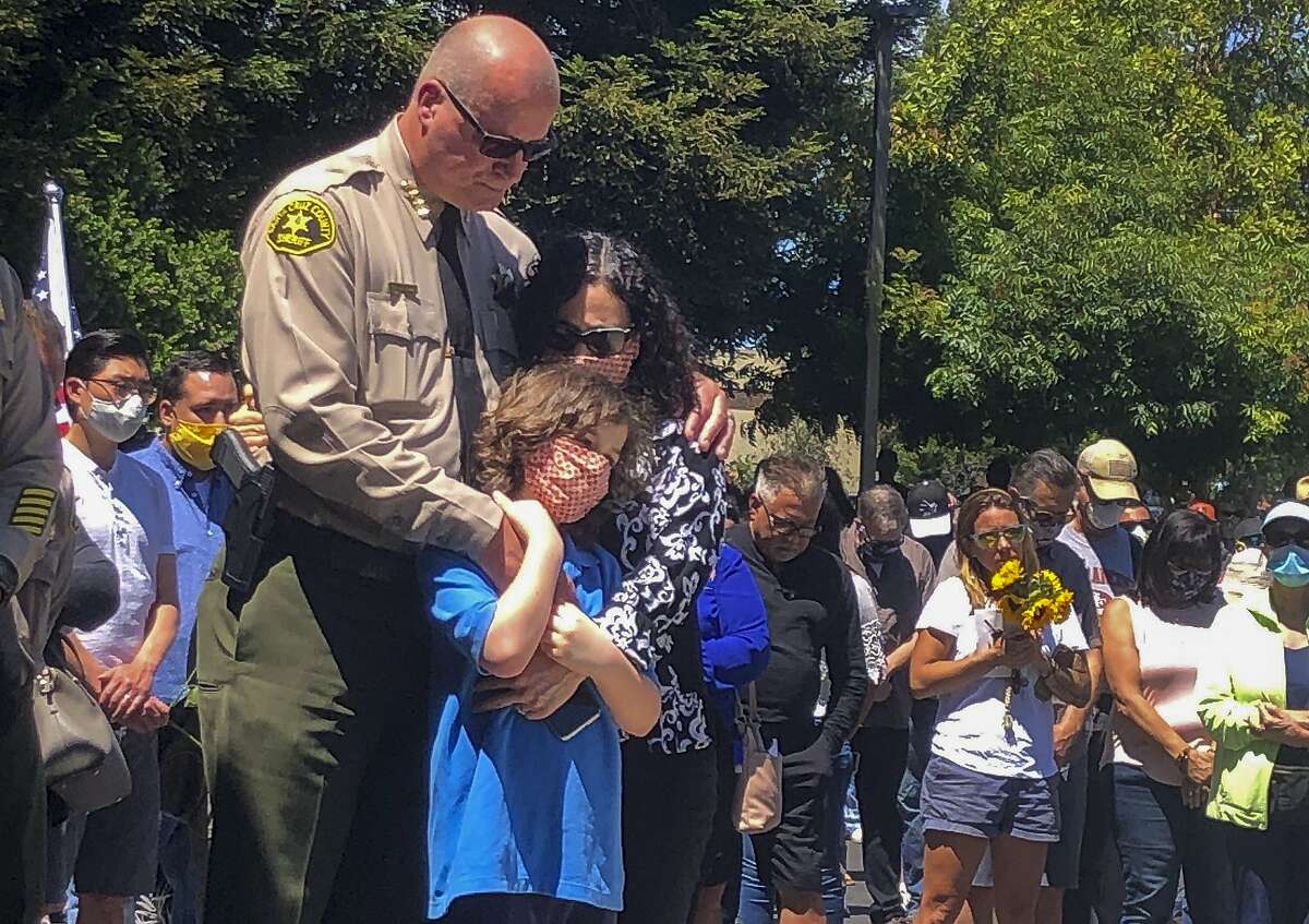 Santa Cruz Sheriff Jim Hart stands with his family, as more than a thousand people gather outside the Santa Cruz County Sheriff-Coroner's Office to pay their respects in Santa Cruz, Calif., Sunday, June 7, 2020. Santa Cruz County Sheriff Sgt. Damon Gutzwiller, 38, was shot and killed in Ben Lomond, an unincorporated area near Santa Cruz. Sheriff Jim Hart said the suspect, Steven Carrillo, was shot during the arrest and is being treated at the hospital. (AP Photo/Martha Mendoza)