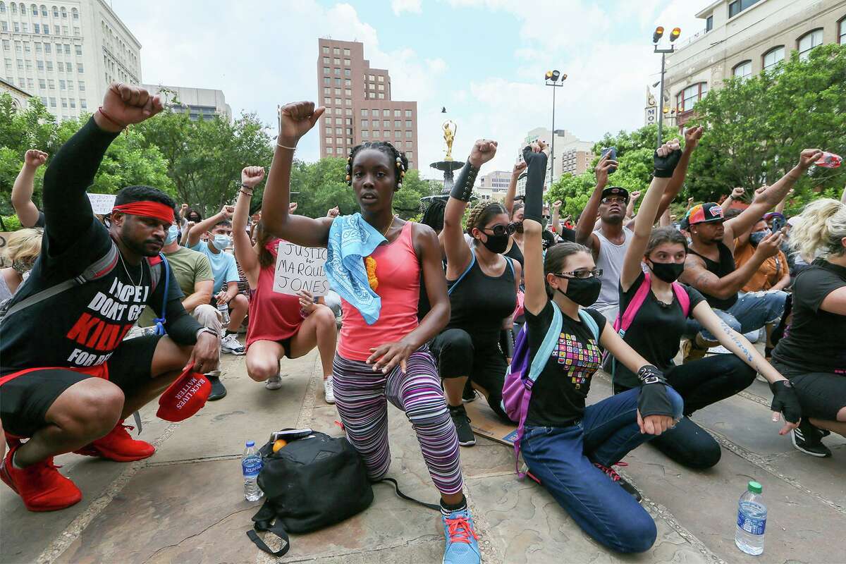 Protesters kneel in a moment of silence in front of the Bexar County Courthouse on Sunday.