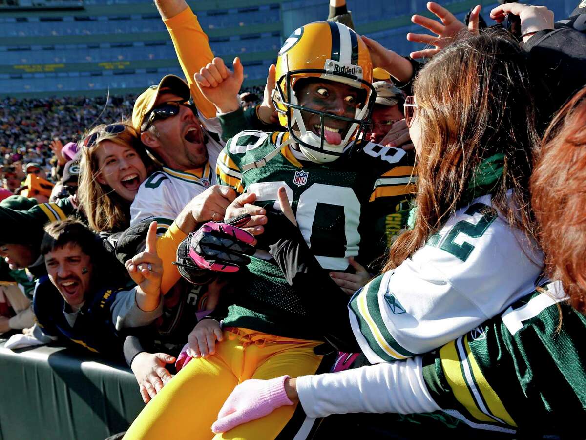 FILE - In this Oct. 28, 2012, file photo, Green Bay Packers wide receiver Donald Driver celebrates a touchdown after doing a Lambeau Leap during the second half of an NFL football game against the Jacksonville Jaguars, in Green Bay, Wisc. As lock-downs are lifted, restrictions on social gatherings eased and life begins to resemble some sense, sports are finally starting to emerge from the coronavirus pandemic. Many sports business experts believe those hardy fans will be the first to return. (AP Photo/Mike Roemer, File)