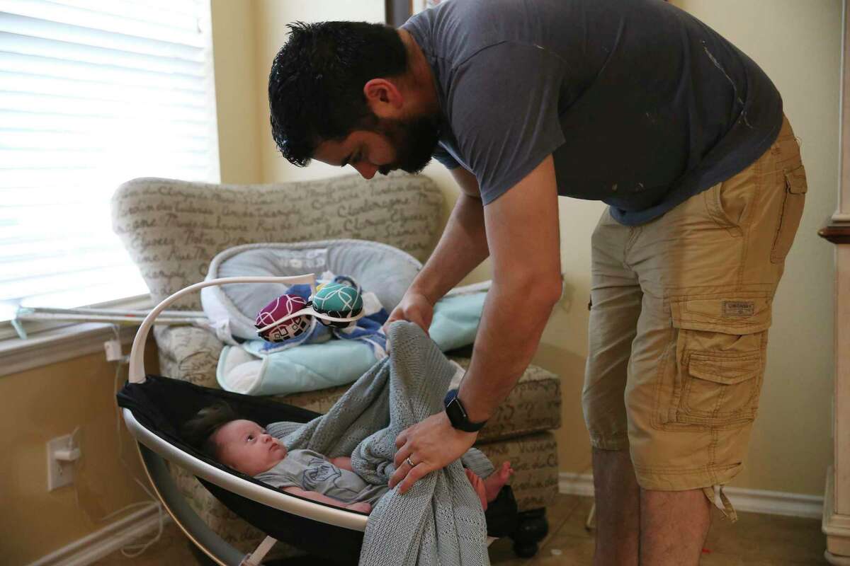 Brandon Beard takes his three-month-old son, Nolan, out of a rocker before a video call with his wife, Teresa, at their home May 21. She is working as a traveling nurse on an eight-week assignment at a hospital in Brooklyn. At this point, she had two weeks left on her assignment.