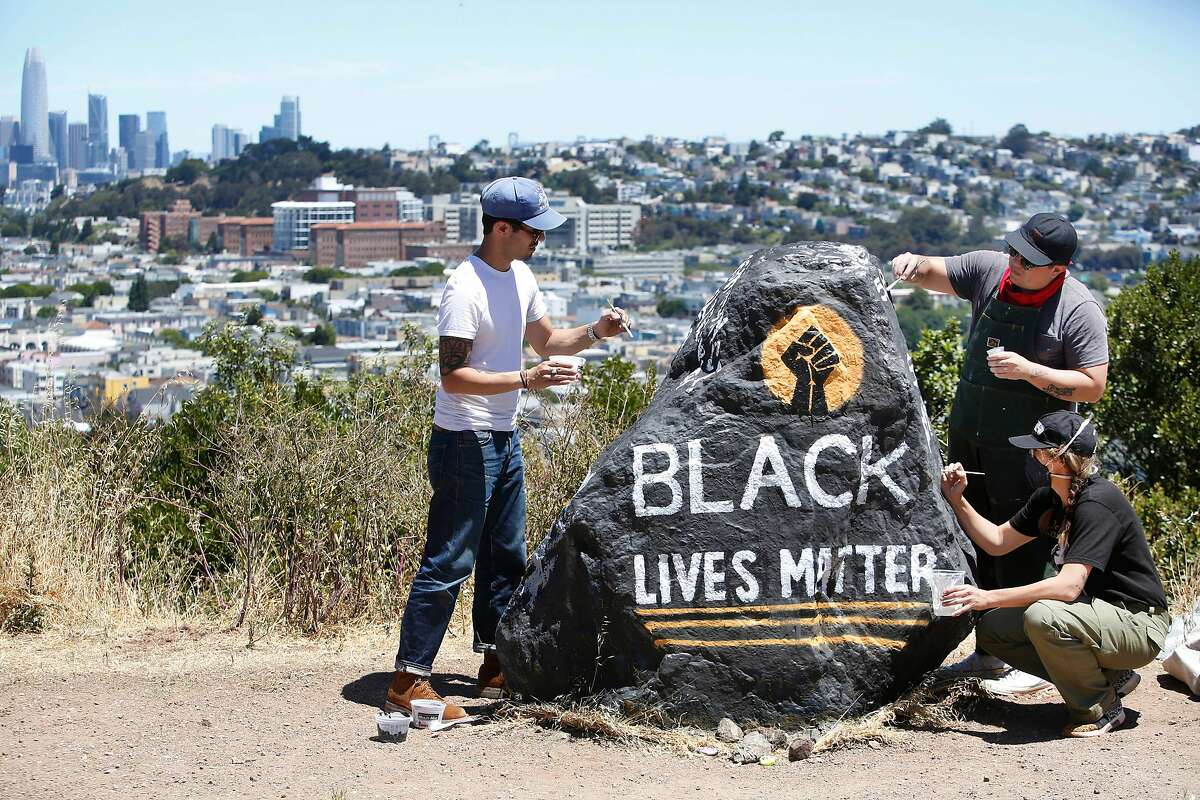 Kseniya Makarova (right front); Micah Rivera (right back) and Manny Fabregas (left), all of San Francisco, paint a rock on Folsom Street for Black Lives Matter on Monday, June 8, 2020 in San Francisco, Calif. Makarova painted the rock for the for the first time last Wednesday and had to repaint it after it was covered with spray paint. Today is the fifth time she is repainting it.