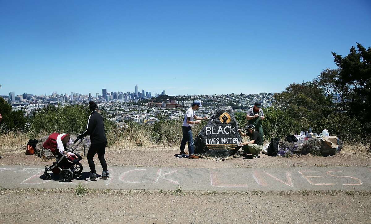 Kseniya Makarova (right front); Micah Rivera (right back) and Manny Fabregas (second from left), all of San Francisco, paint a rock on Folsom Street for Black Lives Matter on Monday, June 8, 2020 in San Francisco, Calif. Makarova painted the rock for the for the first time last Wednesday and had to repaint it after it was covered with spray paint. Today is the fifth time she is repainting it.