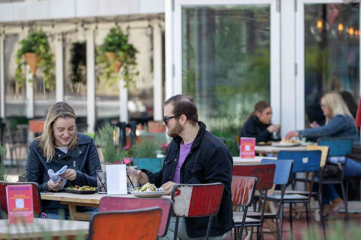 Emily Black, left, and Adam Weinstein have lunch on the outdoor patio of Mexicue restaurant, Wednesday, May 20, 2020, in Stamford, Conn. Restaurants offered outdoor service starting May 20 as part of the first phase of Connecticut's statewide reopening, including in hard-hit Fairfield County on the New York state line. (AP Photo/Mary Altaffer)
