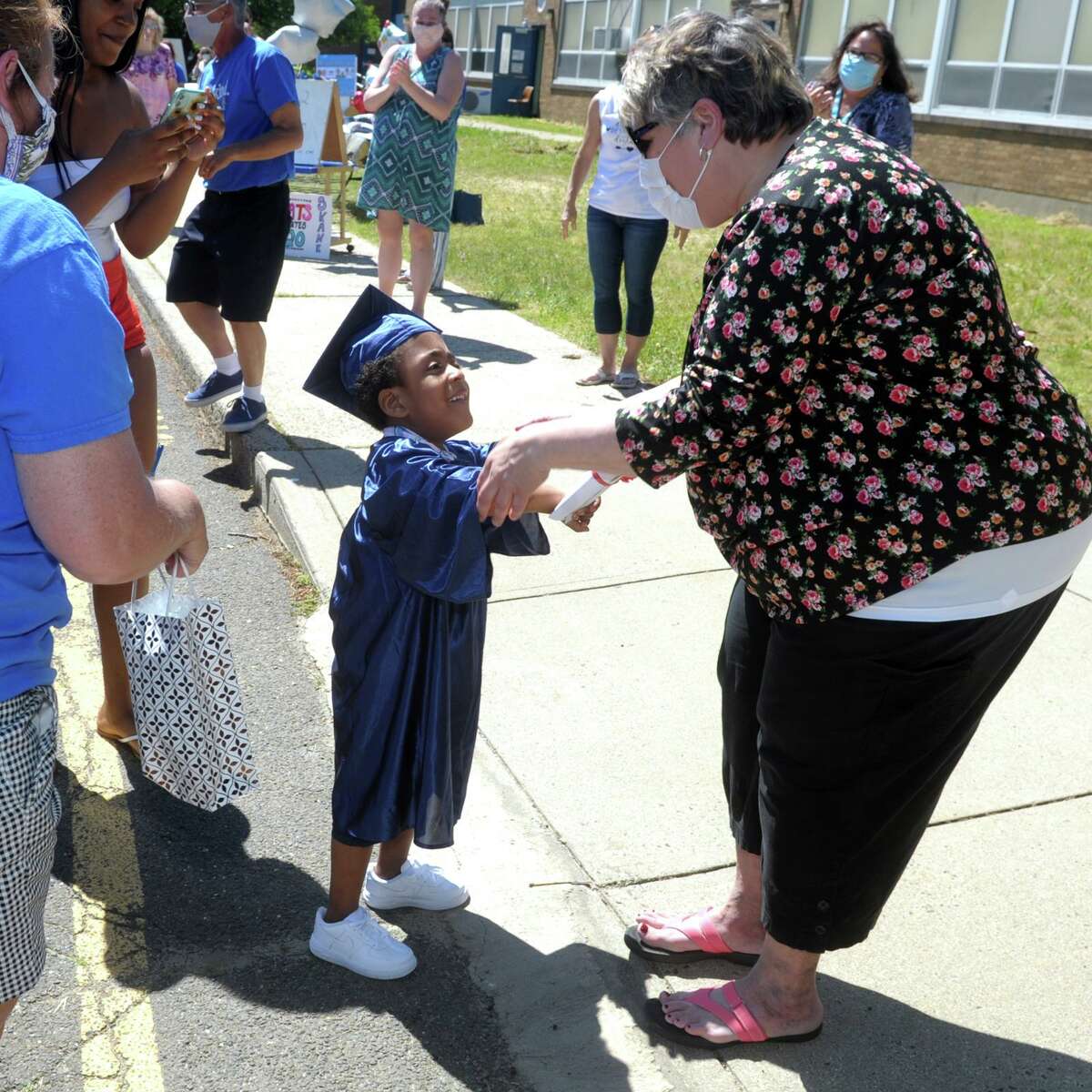 Jordon Thompson is greeted by teacher Sally Pace as his arrives to pick up his diploma at Skane School, in Bridgeport, Conn. June 8, 2020. The school held a drive-through graduation event for Pre-k students on Monday.