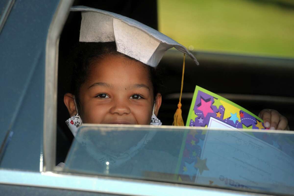 Bella Smart smiles from the back seat of her family’s car as she arrives to pick up her diploma at Skane School, in Bridgeport, Conn. June 8, 2020. The school held a drive-through graduation event for Pre-k students on Monday.