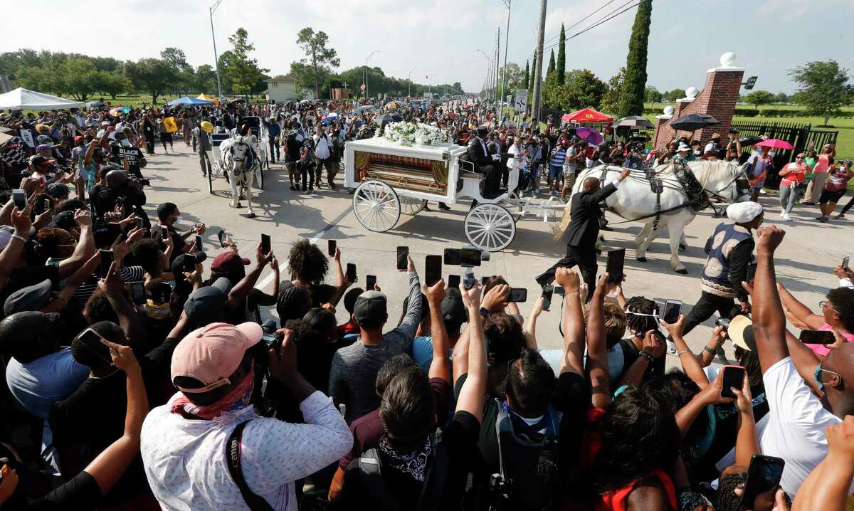 People gather around as the horse drawn carriage carrying the body of George Floyd makes the turn from Cullen Blvd. to Houston Memorial Gardens on Tuesday, June 9, 2020, in Pearland.