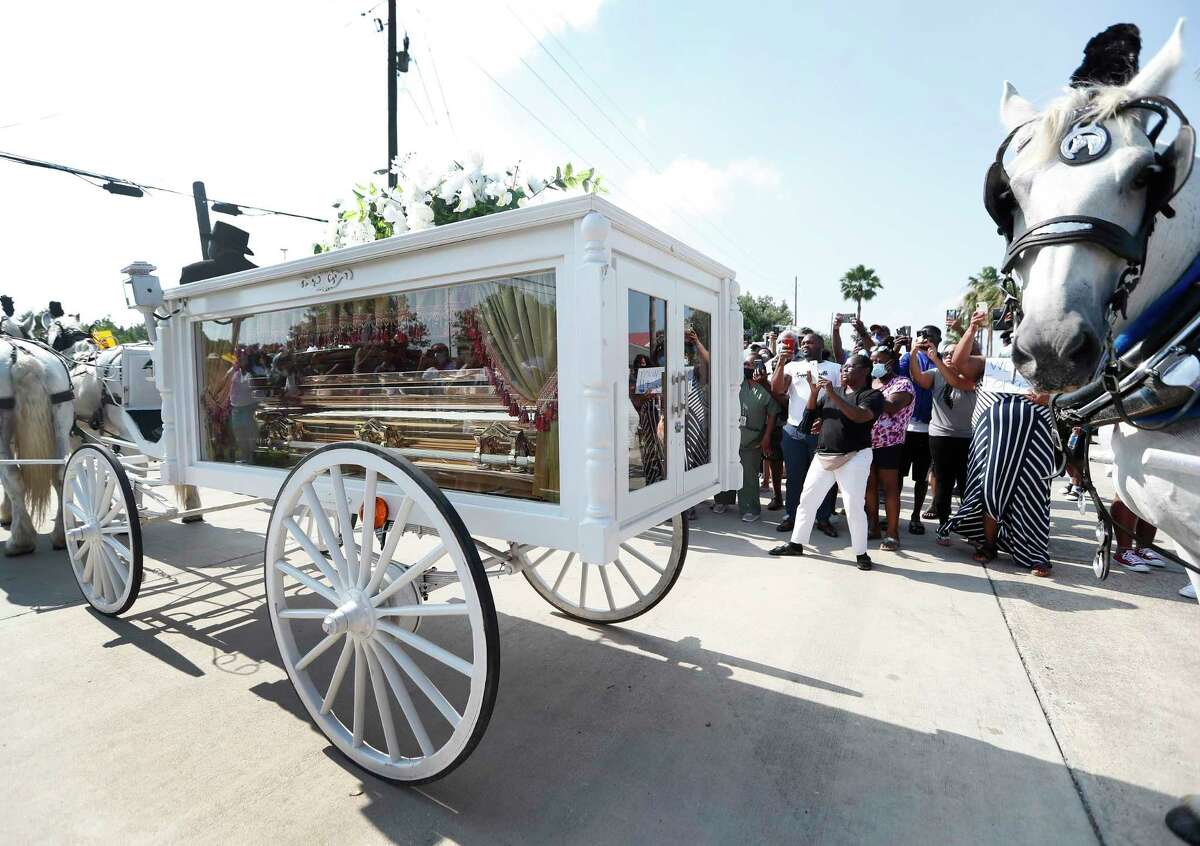 George Floyd's casket carried by a horse drawn carriage inches past the crowd of people along Cullen Blvd. Tuesday, June 8, 2020.
