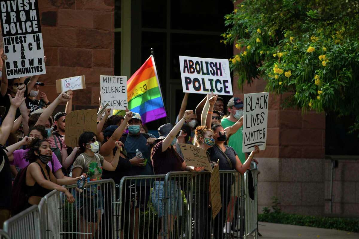 Protesters face law enforcement officers with their signs outside the Paul Elizondo Tower Building in downtown San Antonio, Texas, on June 9, 2020. Protesters rallied a day after Bexar County District Attorney Joe Gonzales said he did not plan to reopen the cases of Marquise Jones, Charles Roundtree and Antronie Scott, all of whom were killed by San Antonio police officers.