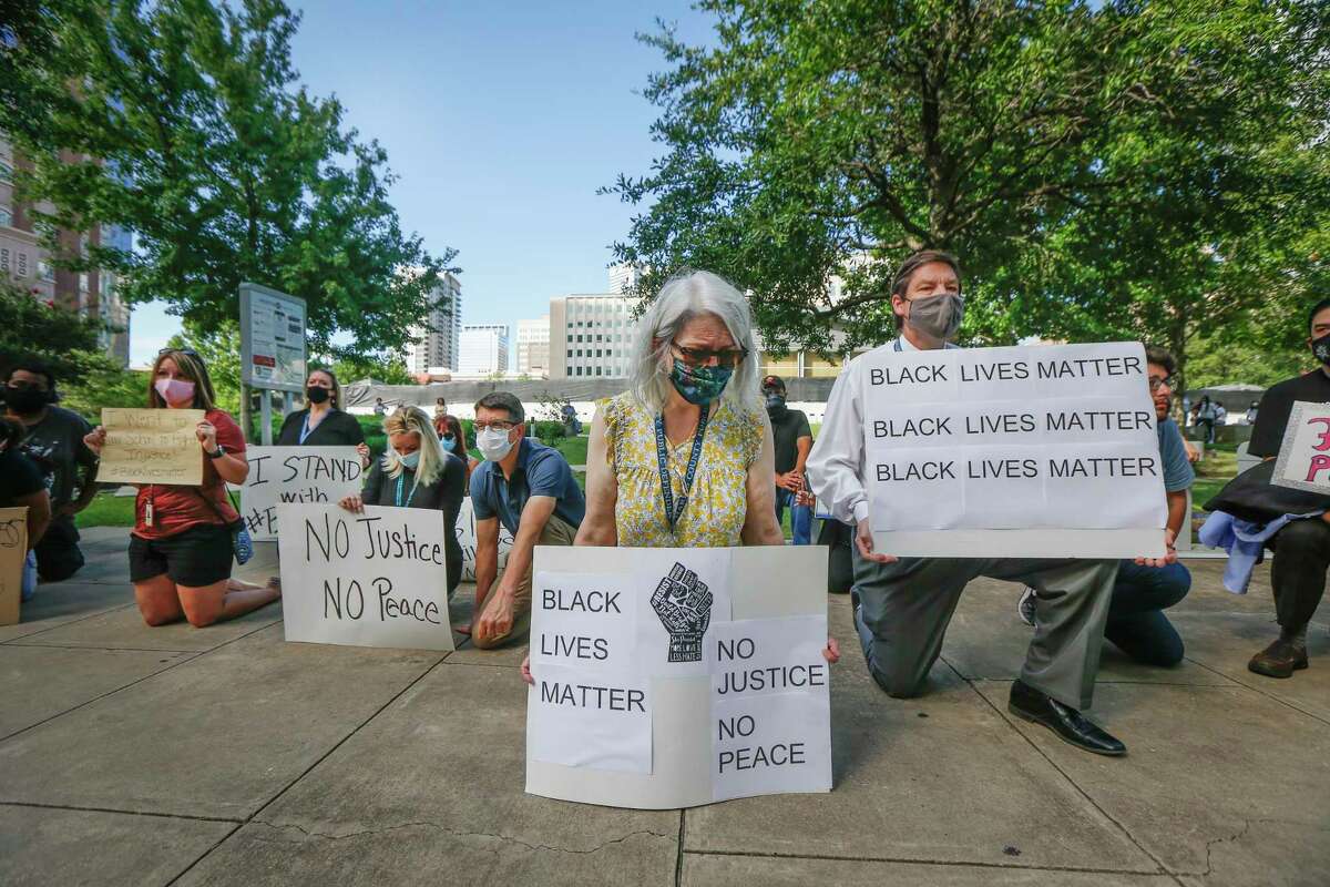 Jani Maselli (center) takes a knee to acknowledge the amount of time that Derek Chauvin kneeled into the neck of George Floyd as they joined other Public Defenders, family and friends in support of black lives matter across from the Harris County Criminal Justice Center Monday, June 8, 2020, in Houston.