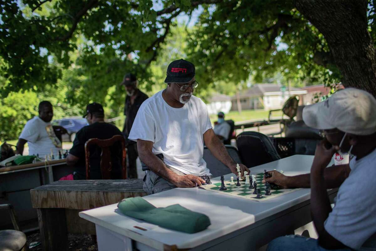Yank Brown plays chess with a friend under a tree in Third Ward on Wednesday, June 10, 2020, in Houston. Brown won that game.
