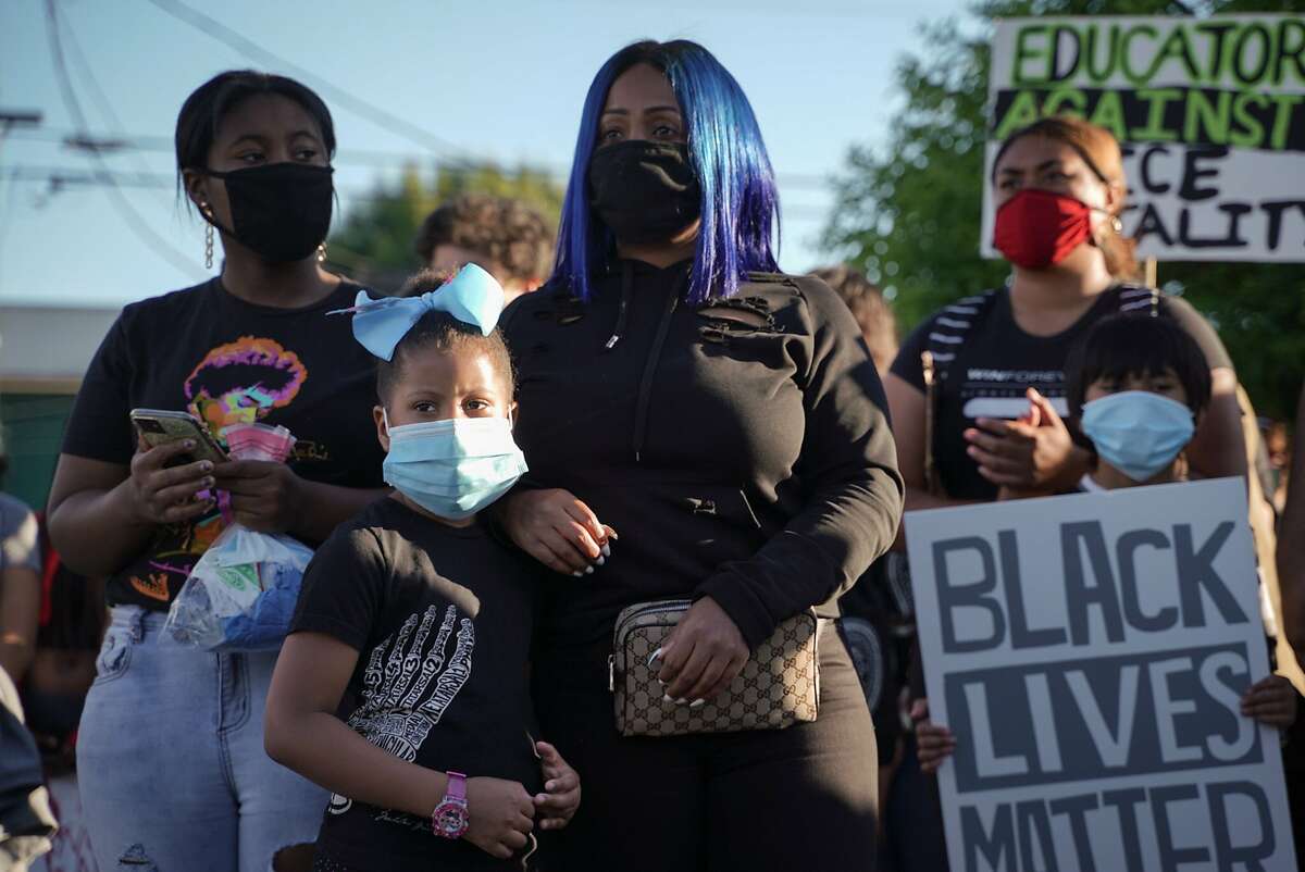 (Left to right) Aalayah, 13, Aminah, 6, and Jojo Williams, 38, of Oakland, attend a youth led protest to defund the Oakland Police Department in Oakland, Calif., on Wednesday, June 10, 2020.