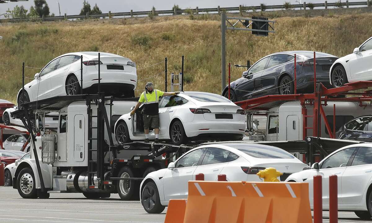 A worker loads a truck with Tesla cars at the Tesla plant Tuesday, May 12, 2020, in Fremont, Calif. Tesla CEO Elon Musk has emerged as a champion of defying stay-home orders intended to stop the coronavirus from spreading. He reopened Tesla's San Francisco Bay Area factory on Monday and President Donald Trump is supporting that decision. (AP Photo/Ben Margot)
