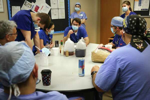 Charge nurse Sam Beckett, center, meets with the ICU nursing staff before the start of an overnight shift. Those working on the COVID-19 ward that night have changed into powder blue surgical scrubs.