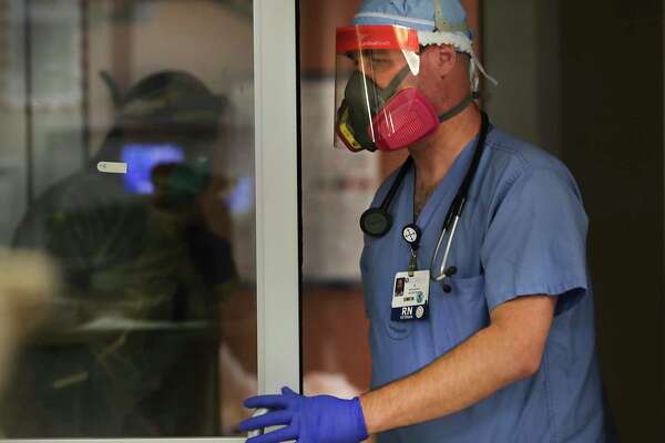 ICU nurse Simon Denton leaves a coronavirus patient’s room. He hasn’t been fazed by the protective equipment necessary to care for COVID-19 patients.