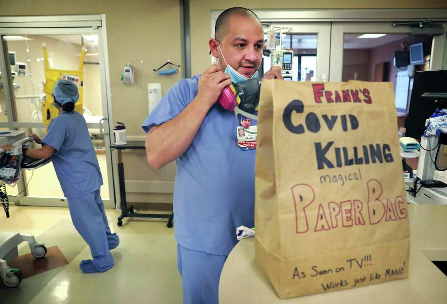 Nurse Frank Salinas puts on his respirator, which he wears while working with patients in the COVID-19 intensive care unit at Northeast Baptist Hospital. The nursing staff store their protective gear in paper bags that several have decorated. Photo: Bob Owen / ©2020 San Antonio Express-News