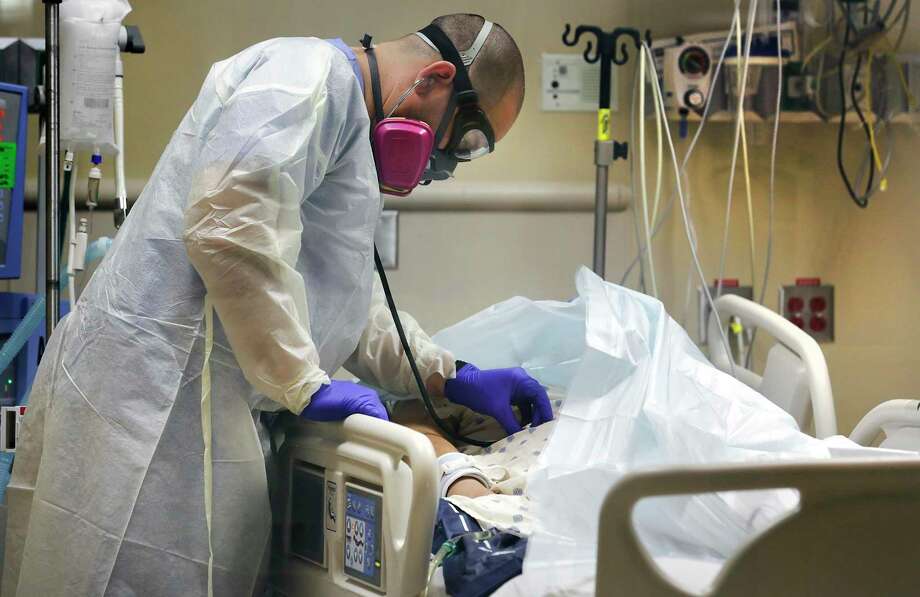 Nurse Frank Salinas examines a COVID-19 patient with his stethoscope in the ICU at Northeast Baptist Hospital. Photo: Bob Owen / ©2020 San Antonio Express-News