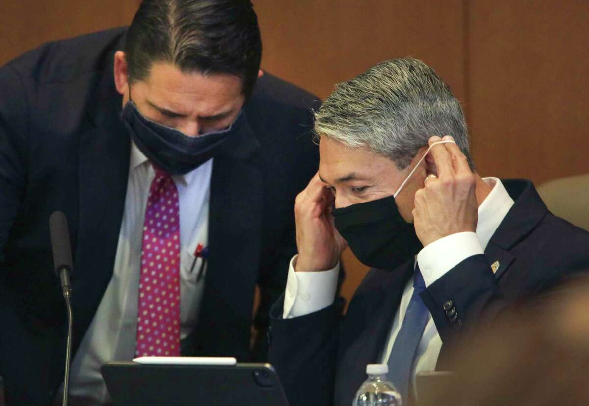 San Antonio Mayor Ron Nerinberg, right, slips on his mask as he listens to City Manager Erik Walsh at a meeting last week. The City Council heard a sobering projection of slow economic recovery and the need for budget cuts at a meeting Thursday.