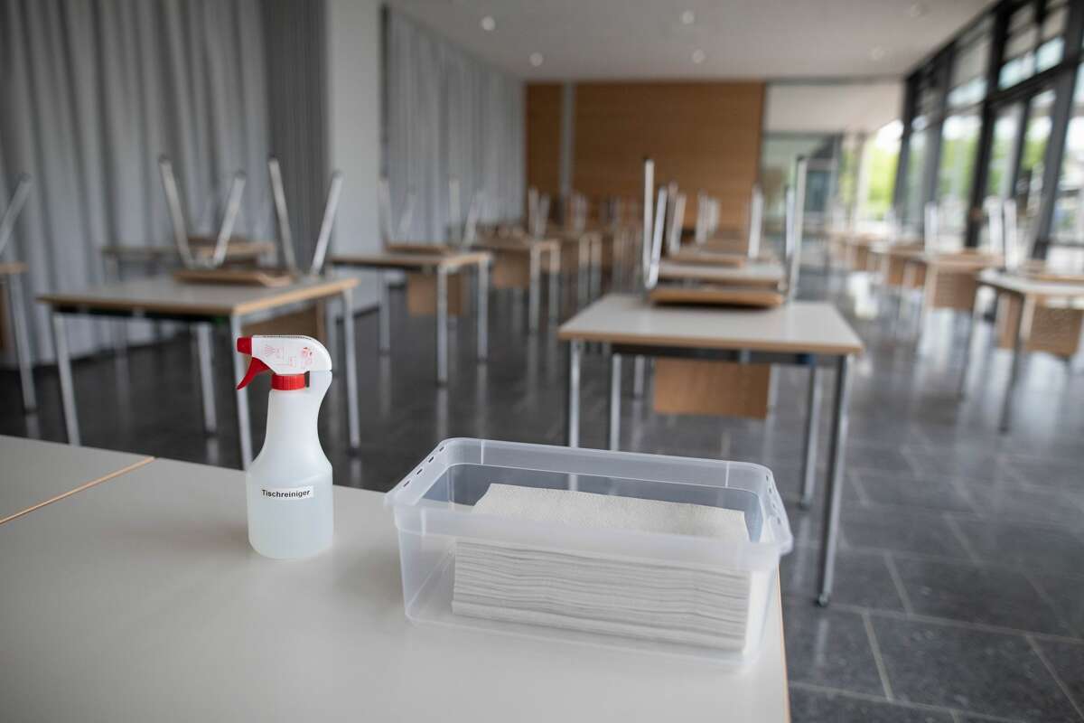 10 June 2020, Baden-Wuerttemberg, Bad Krozingen: A spray bottle with table cleaner and a bowl with paper towels are standing on a desk in a classroom of the upper school in the Kreisgymnasium in Bad Krozingen. Next Monday, June 15th, the schools will again begin a large scale of attendance lessons. To this end, measures have been taken in the schools to prevent infection. Photo: Philipp von Ditfurth/dpa (Photo by Philipp von Ditfurth/picture alliance via Getty Images)