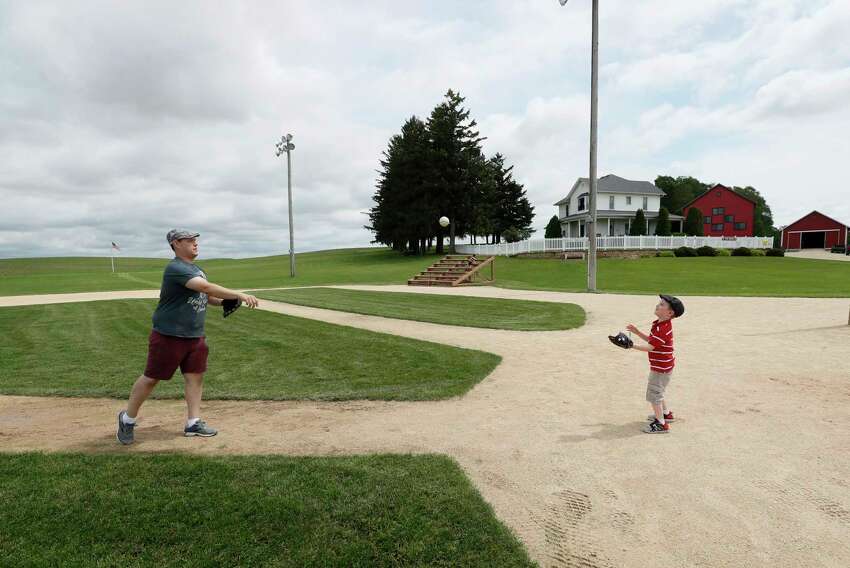 Jeremiah Bronson, of Ames, Iowa, plays catch with his sone Ben, right, on the field at the Field of Dreams movie site, Friday, June 5, 2020, in Dyersville, Iowa. Major League Baseball is building another field a few hundred yards down a corn-lined path from the famous movie site in eastern Iowa but unlike the original, it's unclear whether teams will show up for a game this time as the league and its players struggle to agree on plans for a coronavirus-shortened season. (AP Photo/Charlie Neibergall)